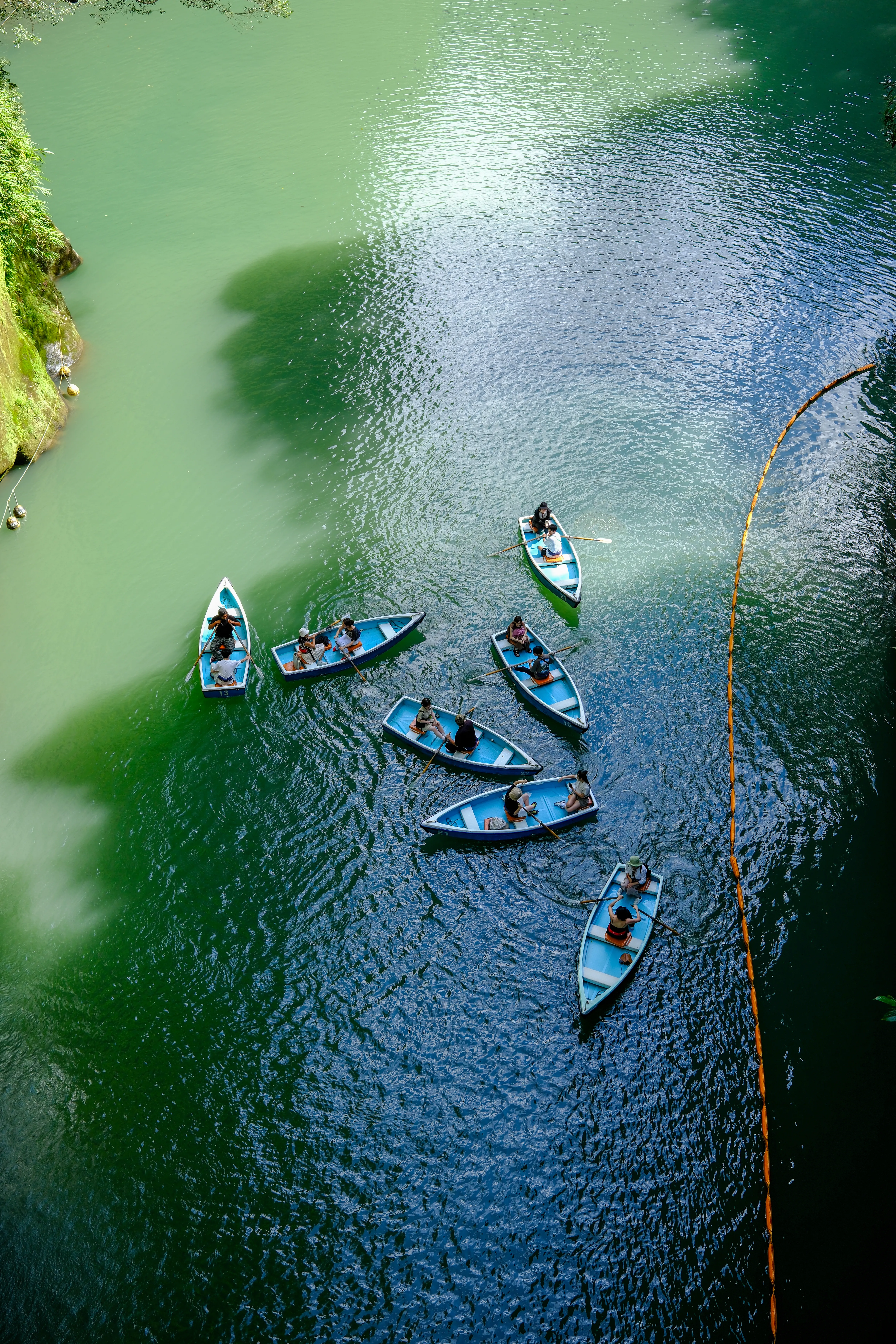 Row boats on a green river seen from above